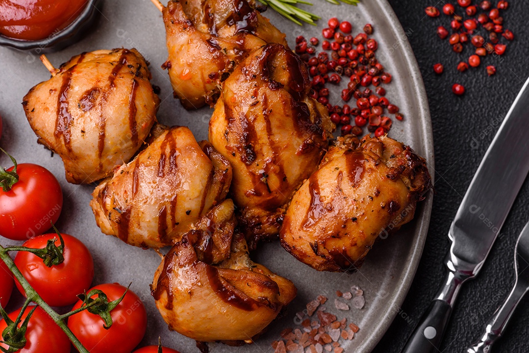 Delicioso frango assado ou espetinho de peru em um espeto com sal e especiarias em um fundo escuro de concreto