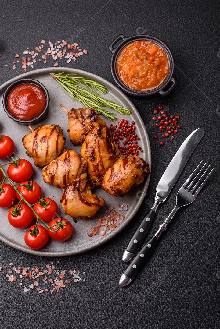 Delicioso frango assado ou espetinho de peru em um espeto com sal e especiarias em um fundo escuro de concreto