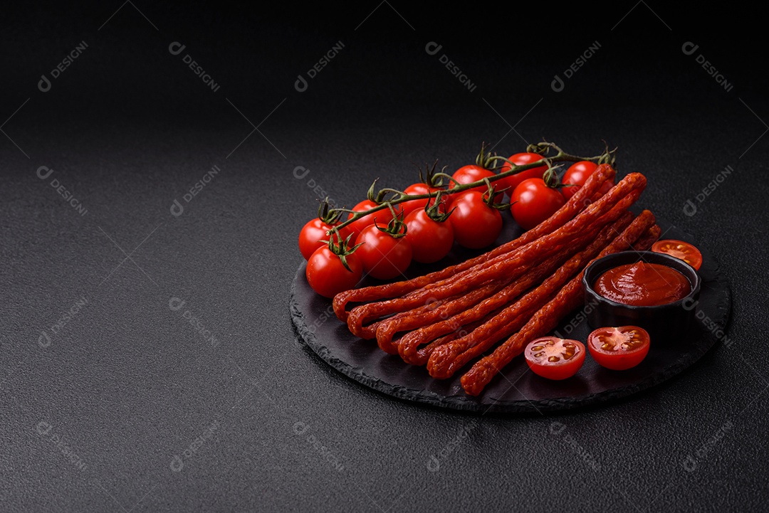 Mini salsichas ou cabanosi defumados com sal e especiarias sobre fundo escuro de concreto