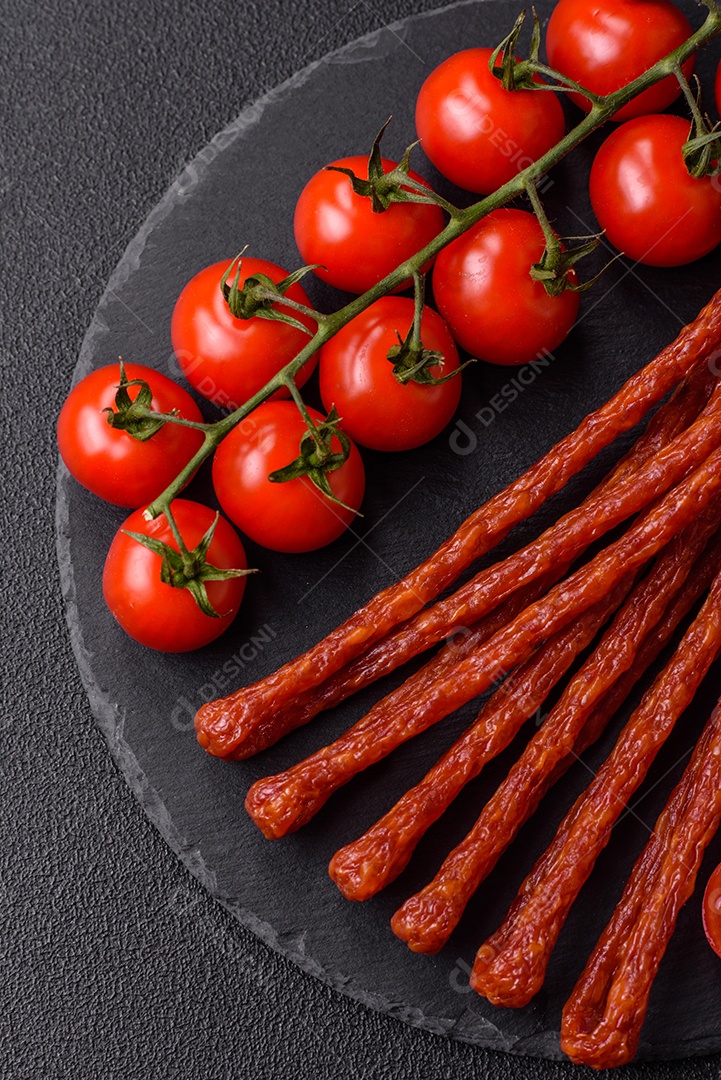 Mini salsichas ou cabanosi defumados com sal e especiarias sobre fundo escuro de concreto