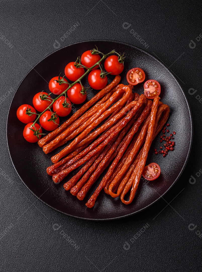 Mini salsichas ou cabanosi defumados com sal e especiarias sobre fundo escuro de concreto