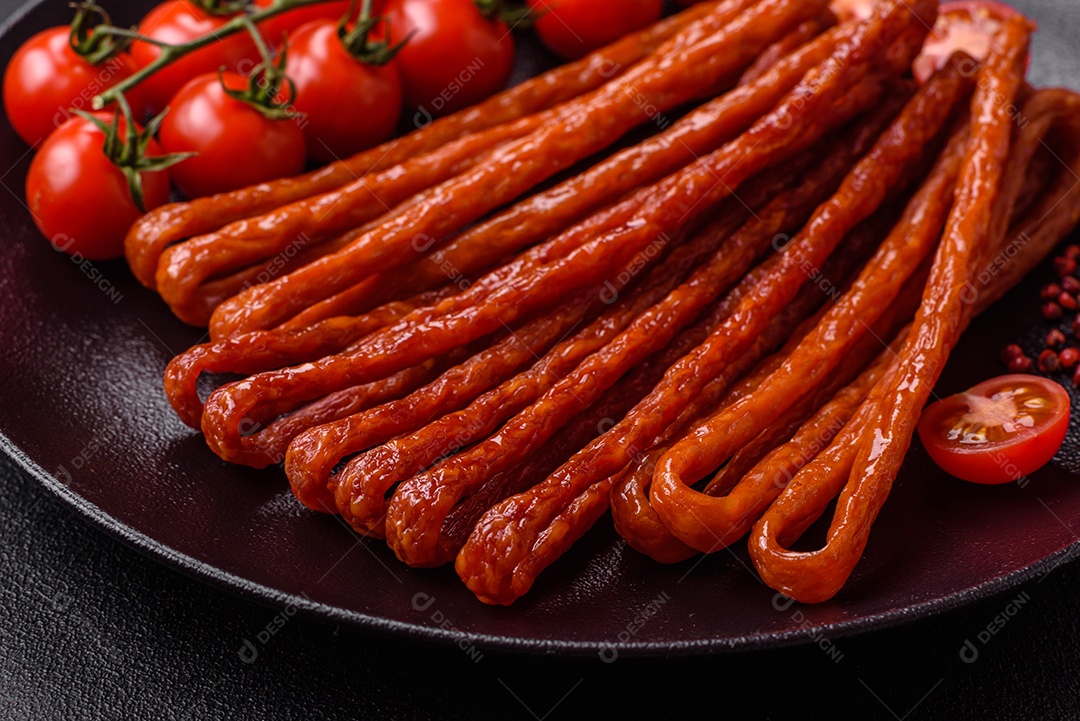 Mini salsichas ou cabanosi defumados com sal e especiarias sobre fundo escuro de concreto