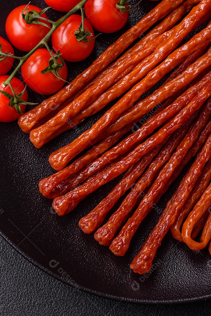 Mini salsichas ou cabanosi defumados com sal e especiarias sobre fundo escuro de concreto