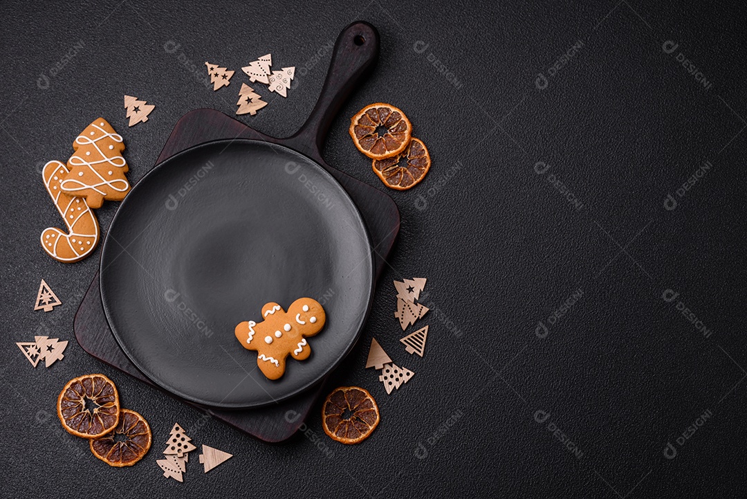 Linda composição festiva de Natal de um prato vazio, pães de gengibre e anis estrelado em um fundo escuro e texturizado