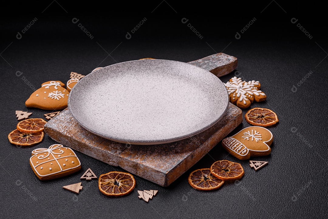 Linda composição festiva de Natal de um prato vazio, pães de gengibre e anis estrelado em um fundo escuro e texturizado