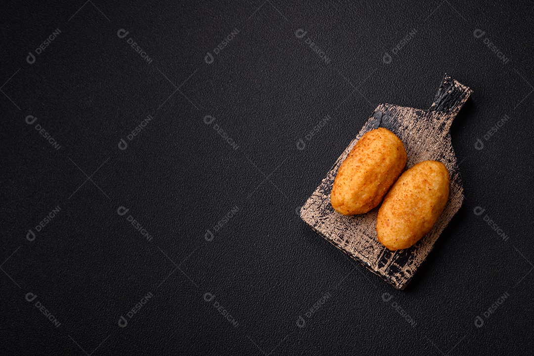 Delicioso frango Kiev ou costeletas de batata com sal, especiarias e ervas sobre um fundo escuro de concreto