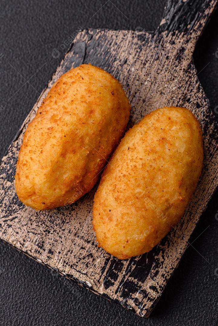 Delicioso frango Kiev ou costeletas de batata com sal, especiarias e ervas sobre um fundo escuro de concreto