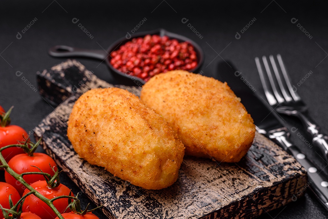 Delicioso frango Kiev ou costeletas de batata com sal, especiarias e ervas sobre um fundo escuro de concreto