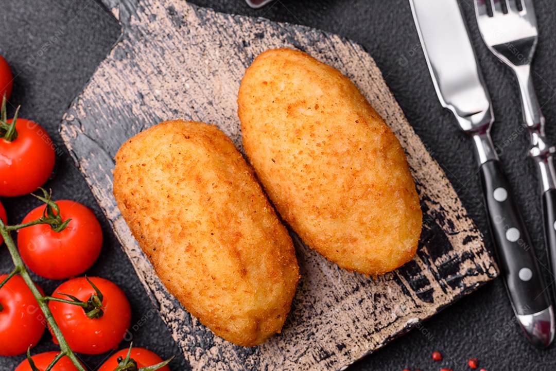 Delicioso frango Kiev ou costeletas de batata com sal, especiarias e ervas sobre um fundo escuro de concreto