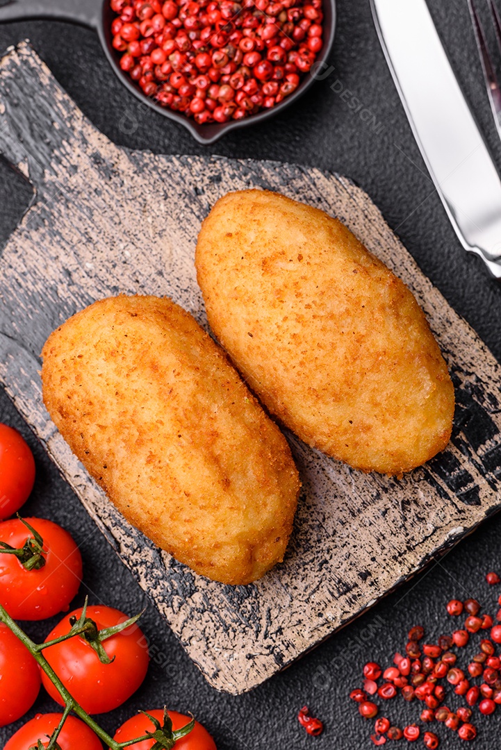 Delicioso frango Kiev ou costeletas de batata com sal, especiarias e ervas sobre um fundo escuro de concreto