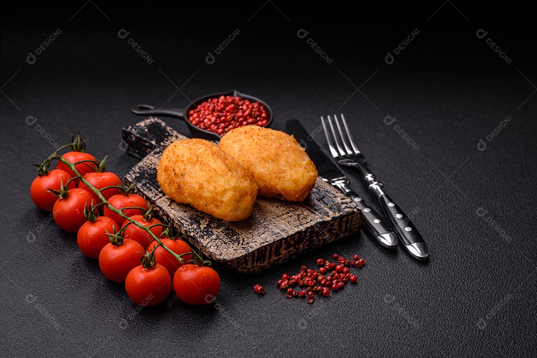 Delicioso frango Kiev ou costeletas de batata com sal, especiarias e ervas sobre um fundo escuro de concreto