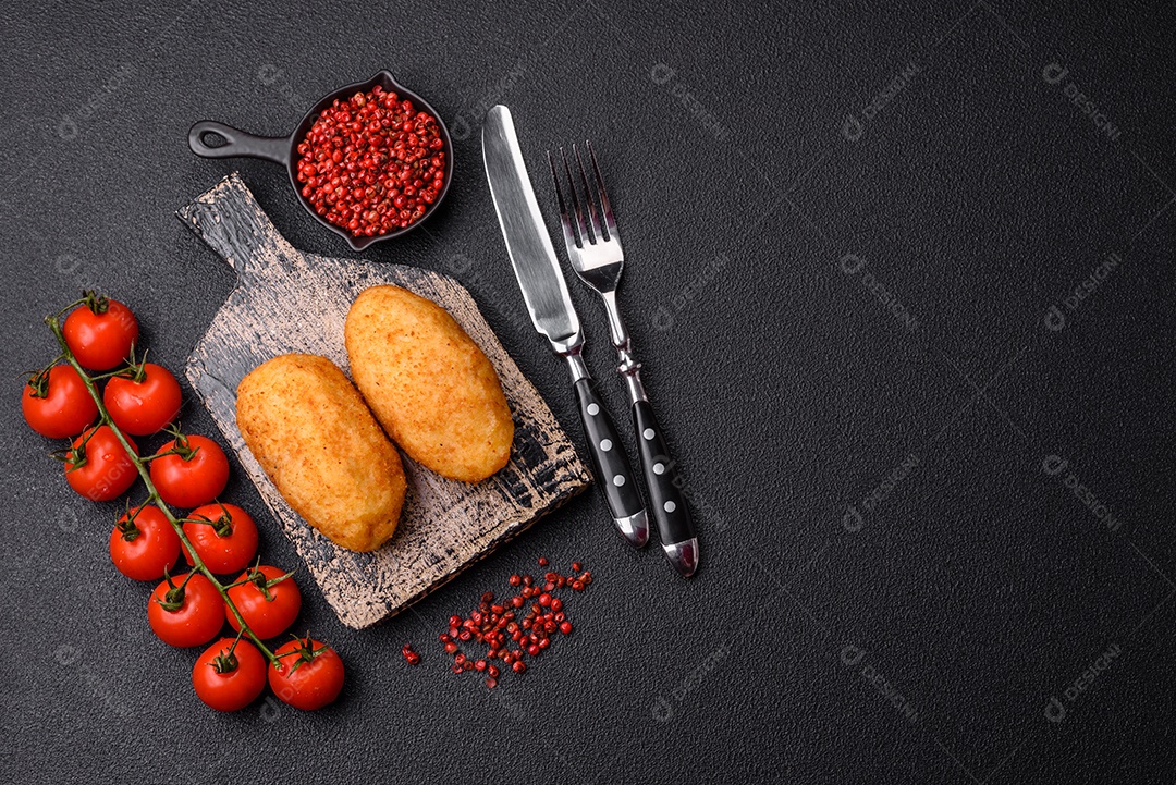 Delicioso frango Kiev ou costeletas de batata com sal, especiarias e ervas sobre um fundo escuro de concreto