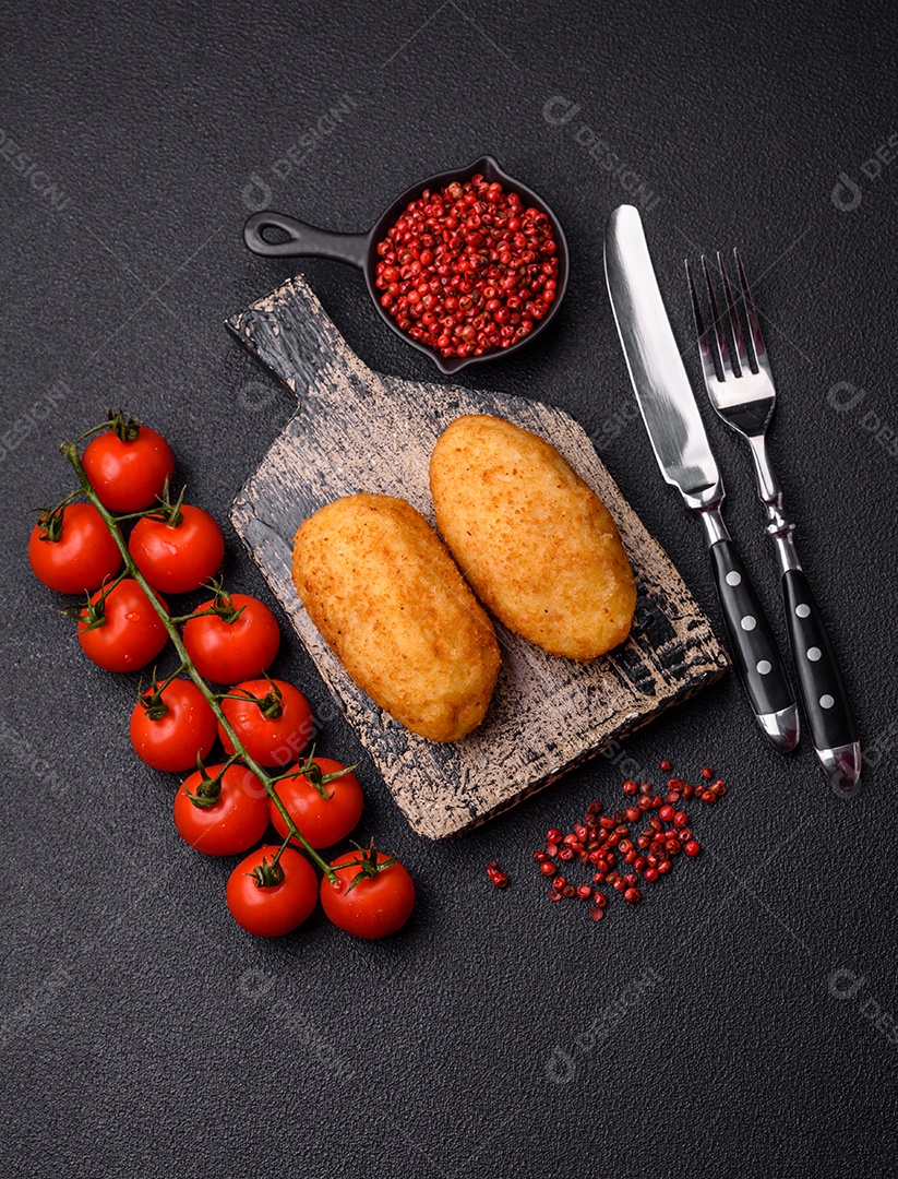 Delicioso frango Kiev ou costeletas de batata com sal, especiarias e ervas sobre um fundo escuro de concreto