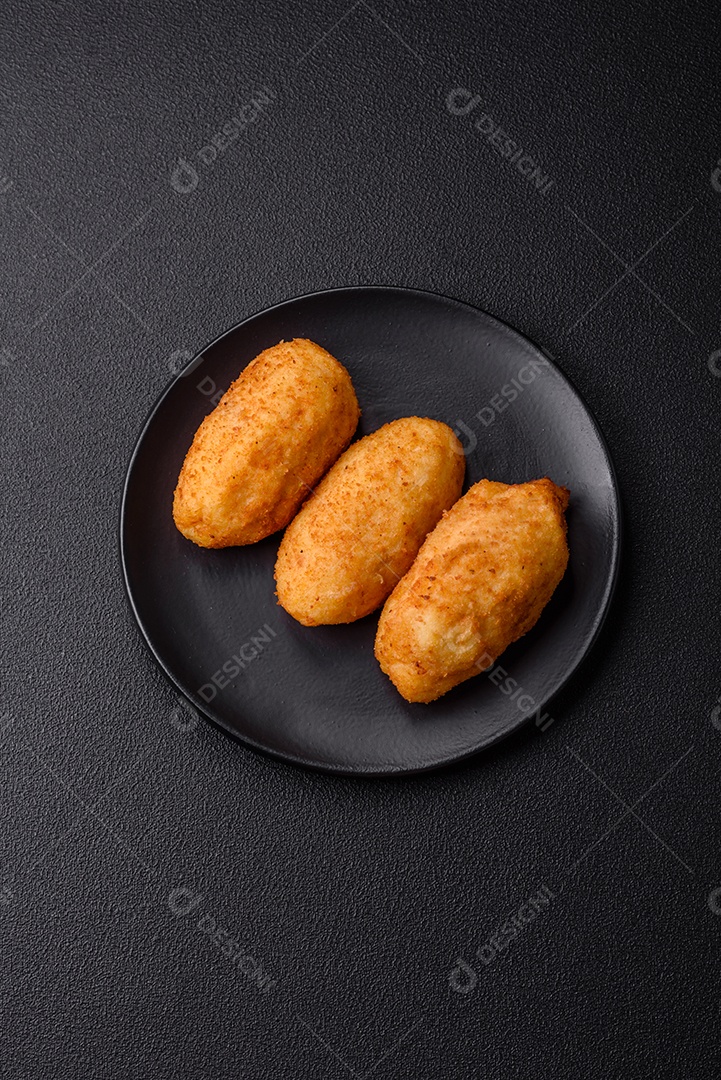 Delicioso frango Kiev ou costeletas de batata com sal, especiarias e ervas sobre um fundo escuro de concreto