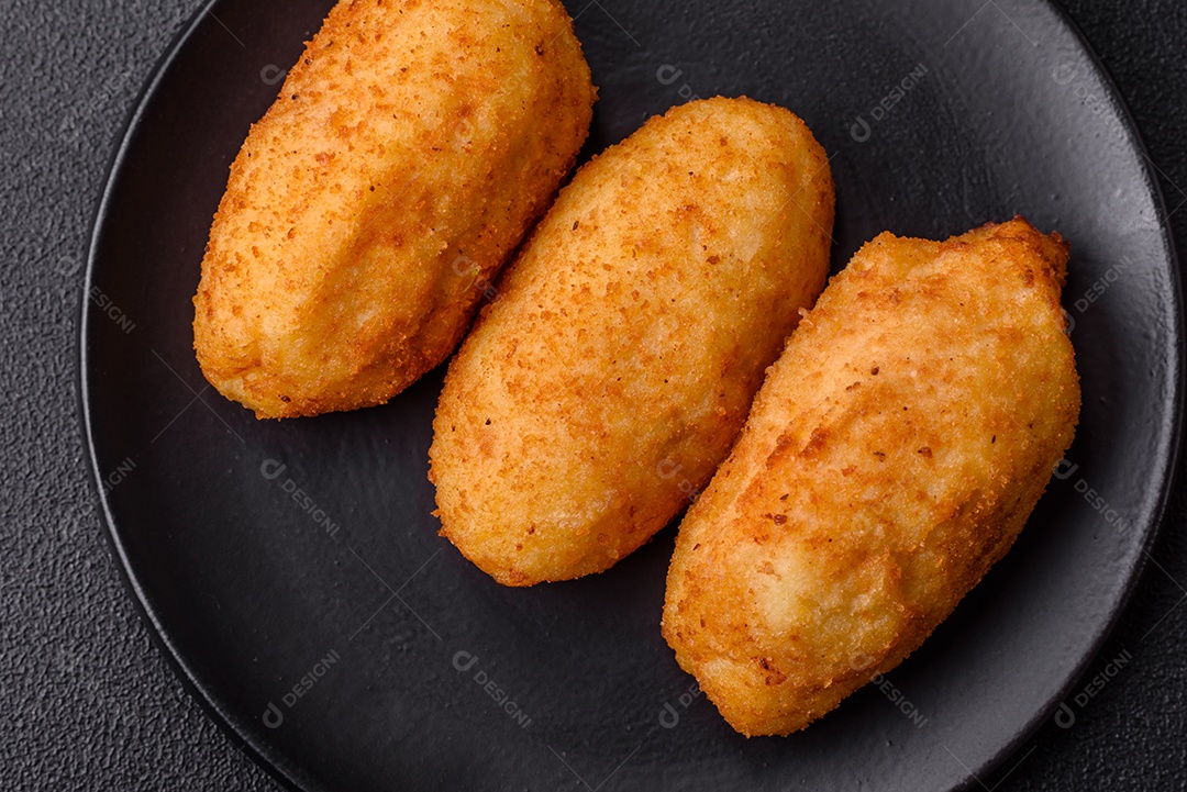 Delicioso frango Kiev ou costeletas de batata com sal, especiarias e ervas sobre um fundo escuro de concreto