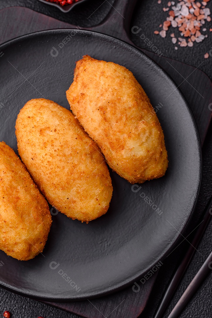 Delicioso frango Kiev ou costeletas de batata com sal, especiarias e ervas sobre um fundo escuro de concreto