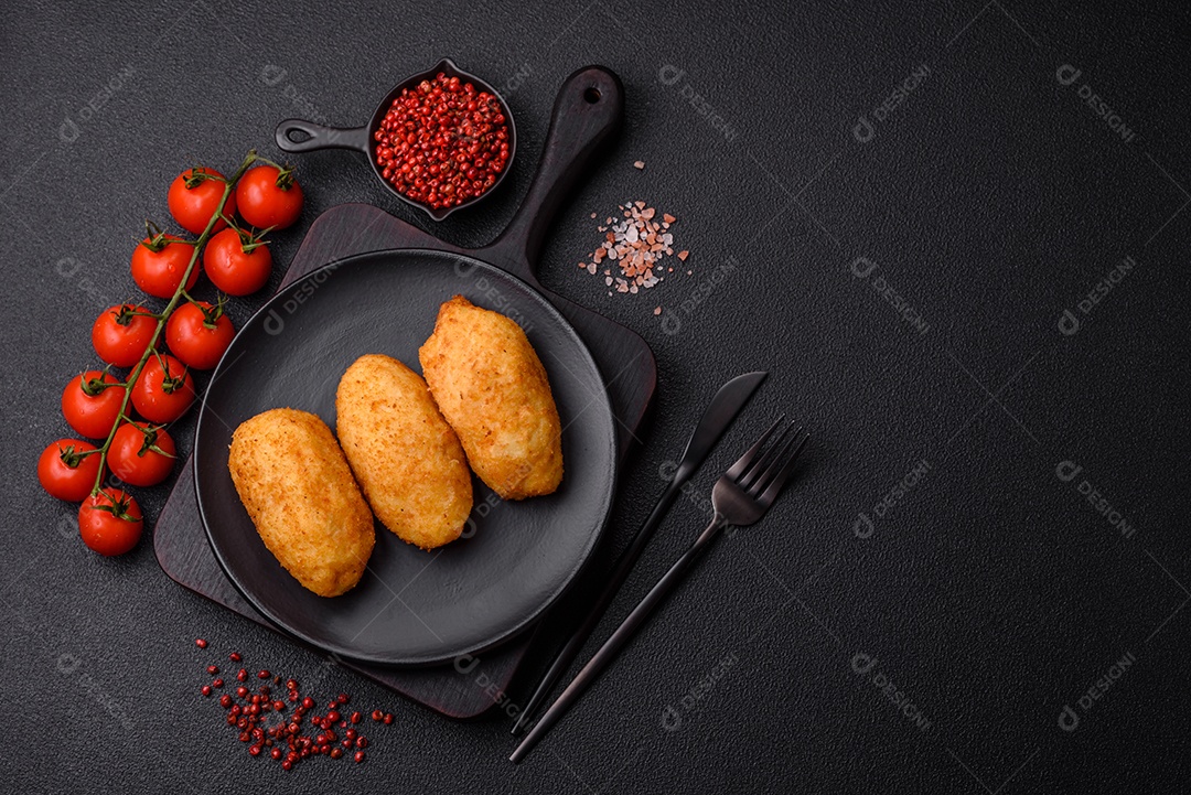 Delicioso frango Kiev ou costeletas de batata com sal, especiarias e ervas sobre um fundo escuro de concreto