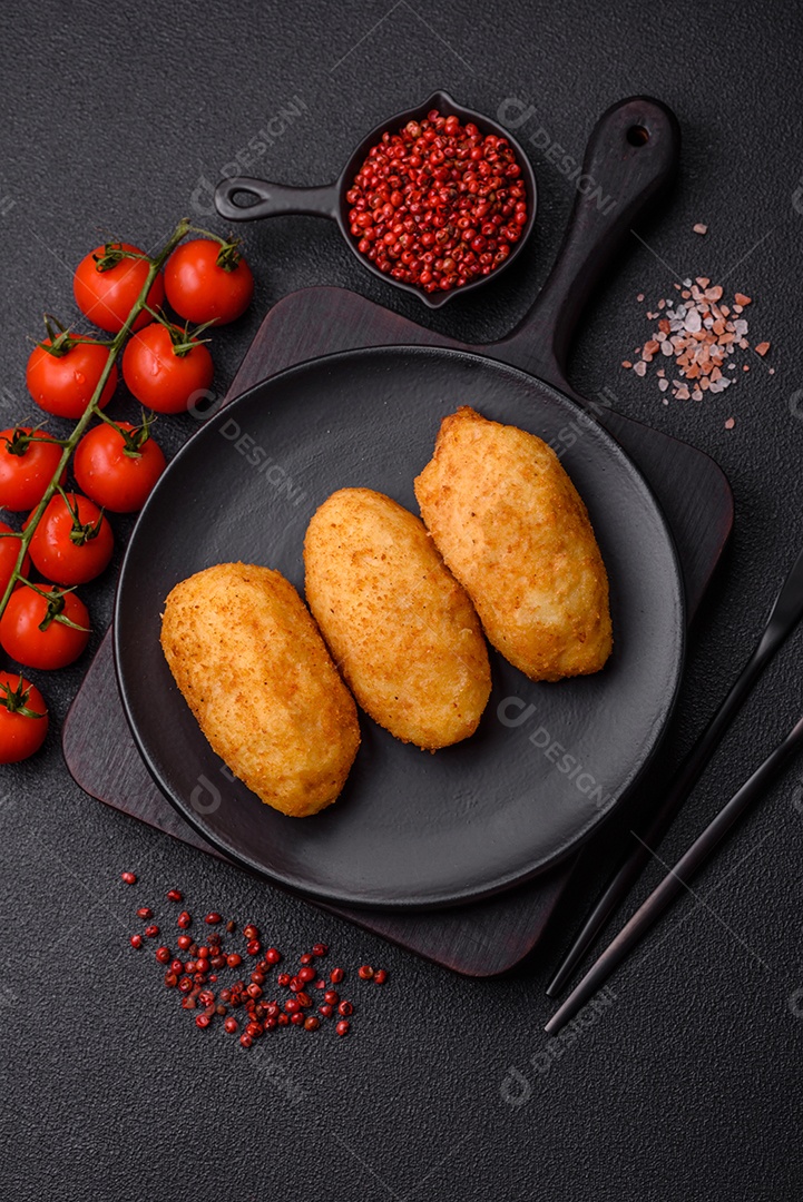 Delicioso frango Kiev ou costeletas de batata com sal, especiarias e ervas sobre um fundo escuro de concreto