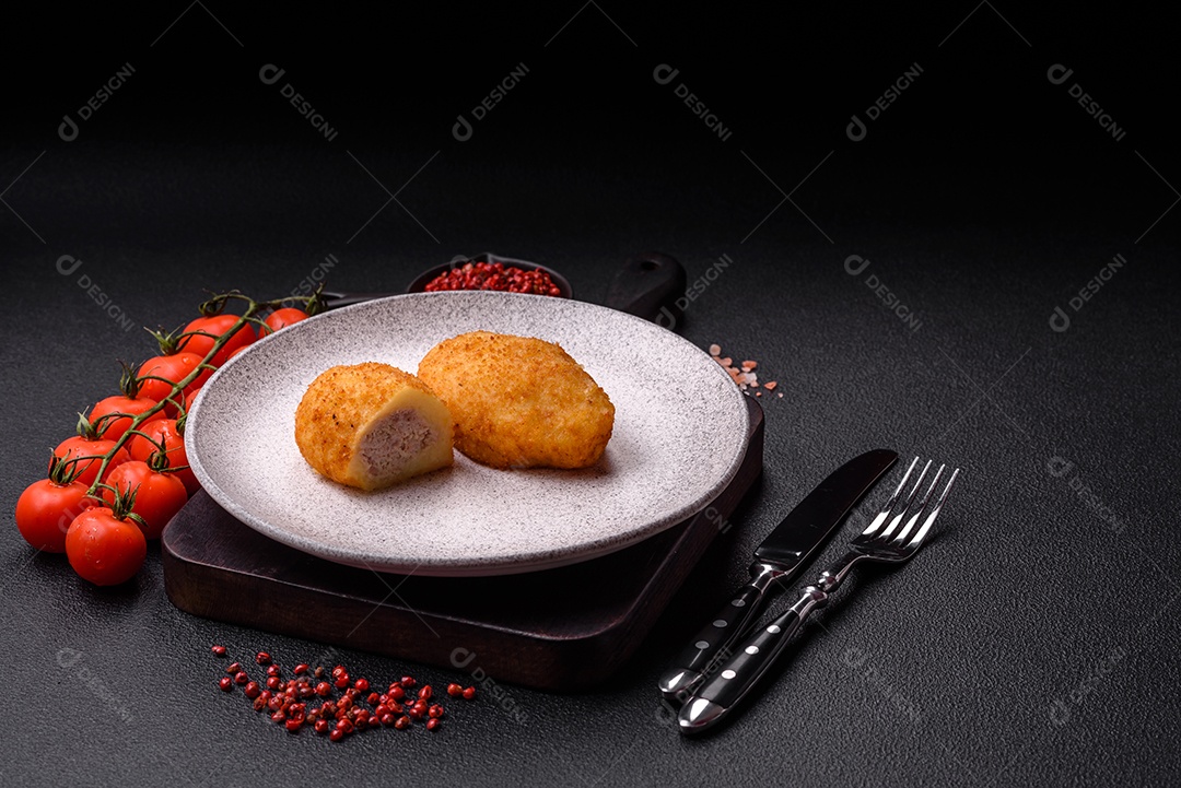 Delicioso frango Kiev ou costeletas de batata com sal, especiarias e ervas sobre um fundo escuro de concreto