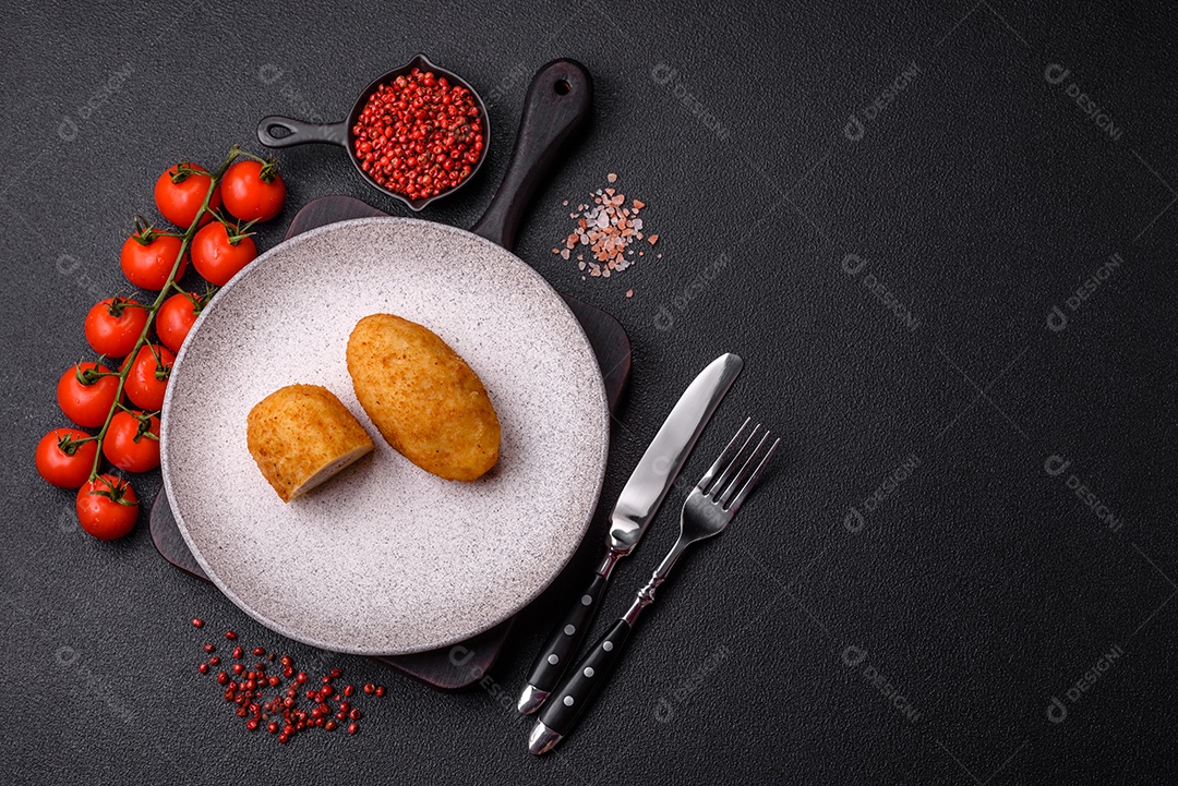 Delicioso frango Kiev ou costeletas de batata com sal, especiarias e ervas sobre um fundo escuro de concreto