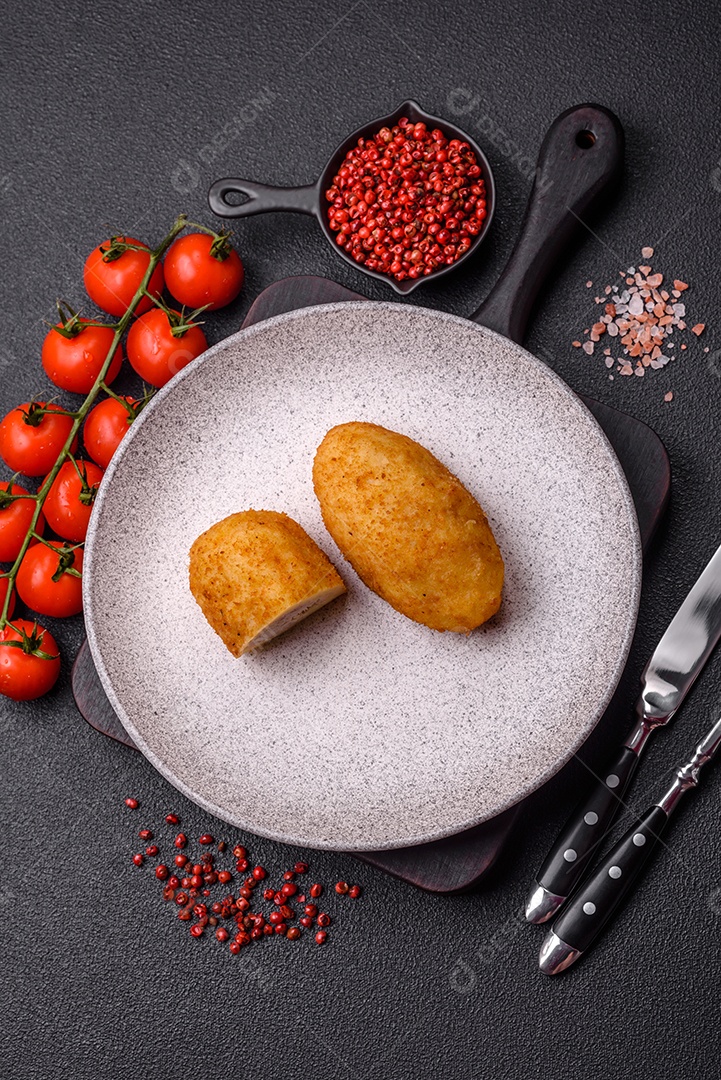 Delicioso frango Kiev ou costeletas de batata com sal, especiarias e ervas sobre um fundo escuro de concreto