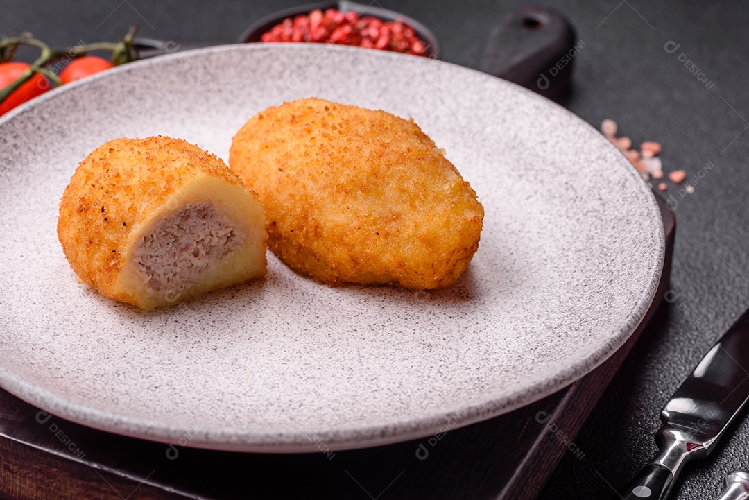 Delicioso frango Kiev ou costeletas de batata com sal, especiarias e ervas sobre um fundo escuro de concreto