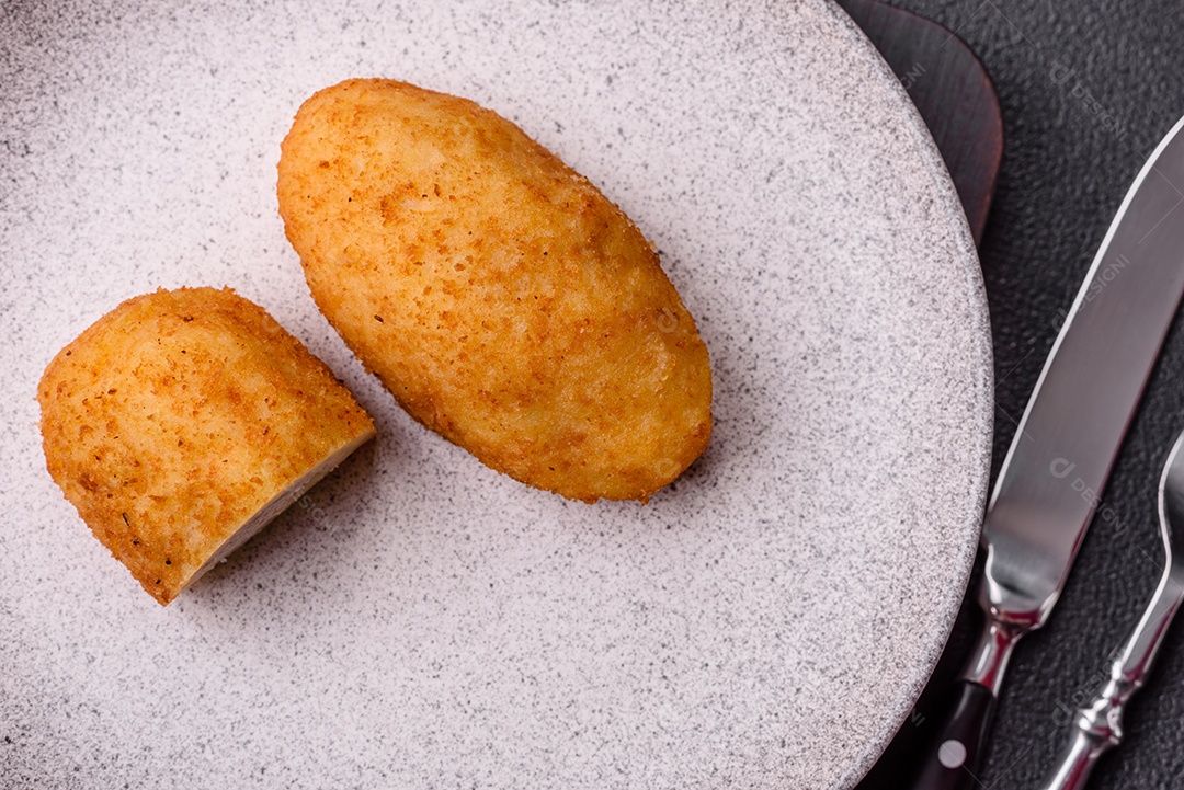 Delicioso frango Kiev ou costeletas de batata com sal, especiarias e ervas sobre um fundo escuro de concreto