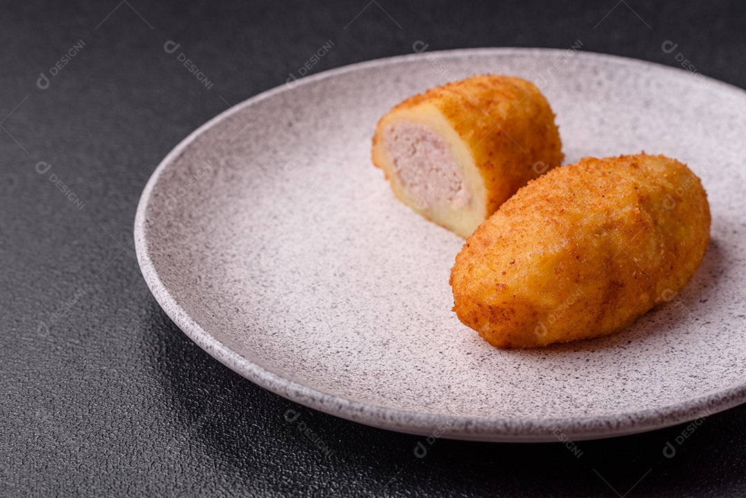 Delicioso frango Kiev ou costeletas de batata com sal, especiarias e ervas sobre um fundo escuro de concreto