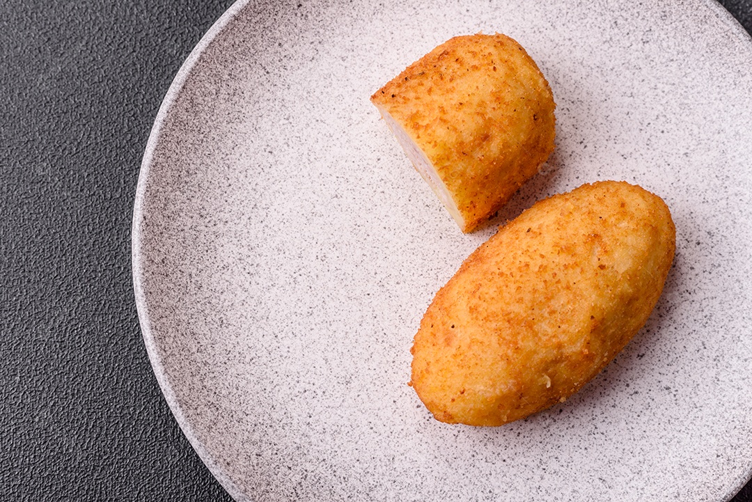 Delicioso frango Kiev ou costeletas de batata com sal, especiarias e ervas sobre um fundo escuro de concreto