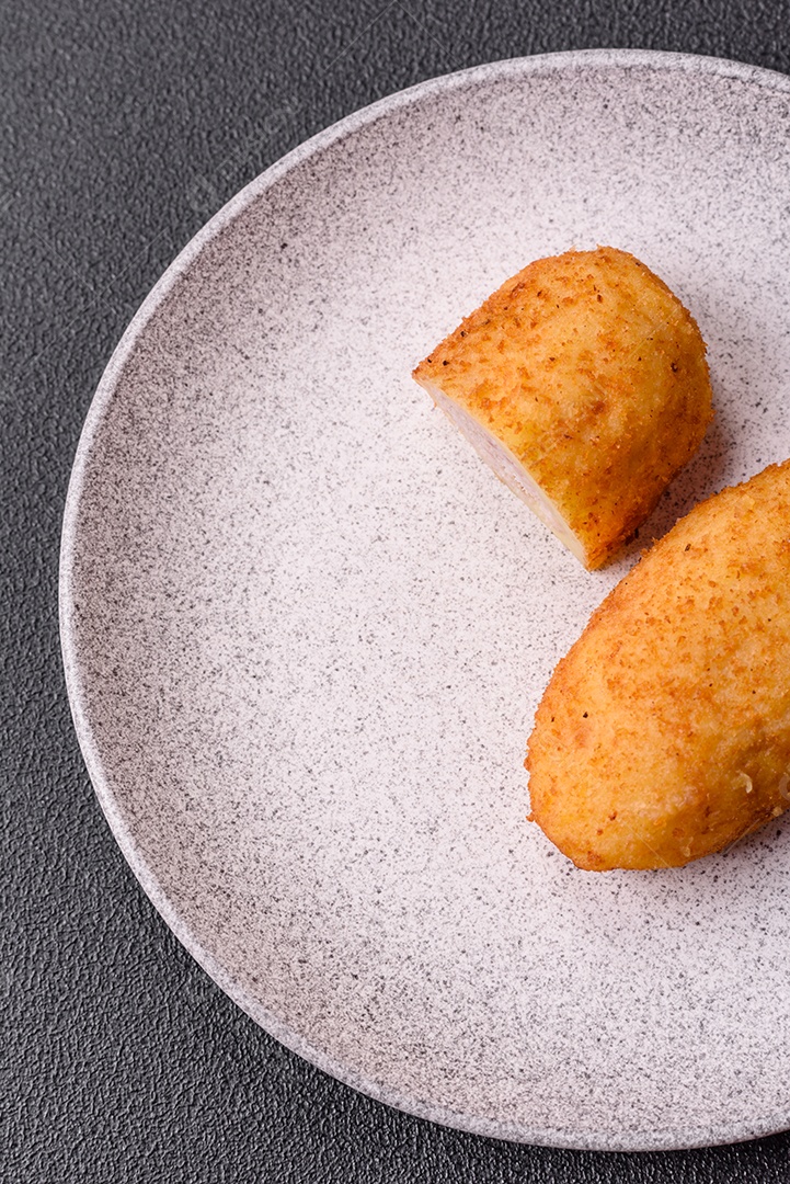 Delicioso frango Kiev ou costeletas de batata com sal, especiarias e ervas sobre um fundo escuro de concreto