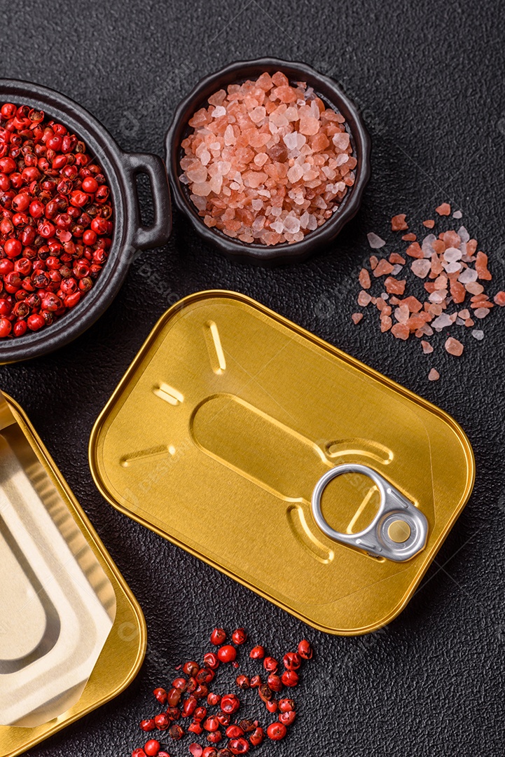 Lata metálica com carne ou peixe enlatado com chave para abri-lo sobre um fundo escuro de concreto