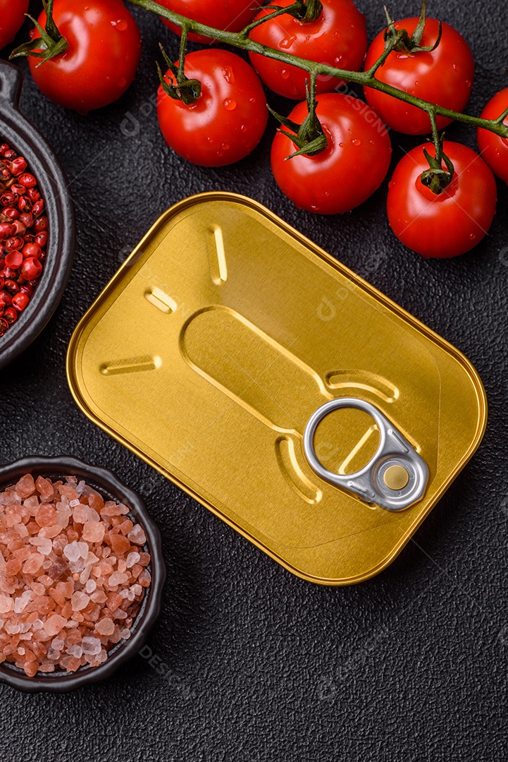 Lata metálica com carne ou peixe enlatado com chave para abri-lo sobre um fundo escuro de concreto