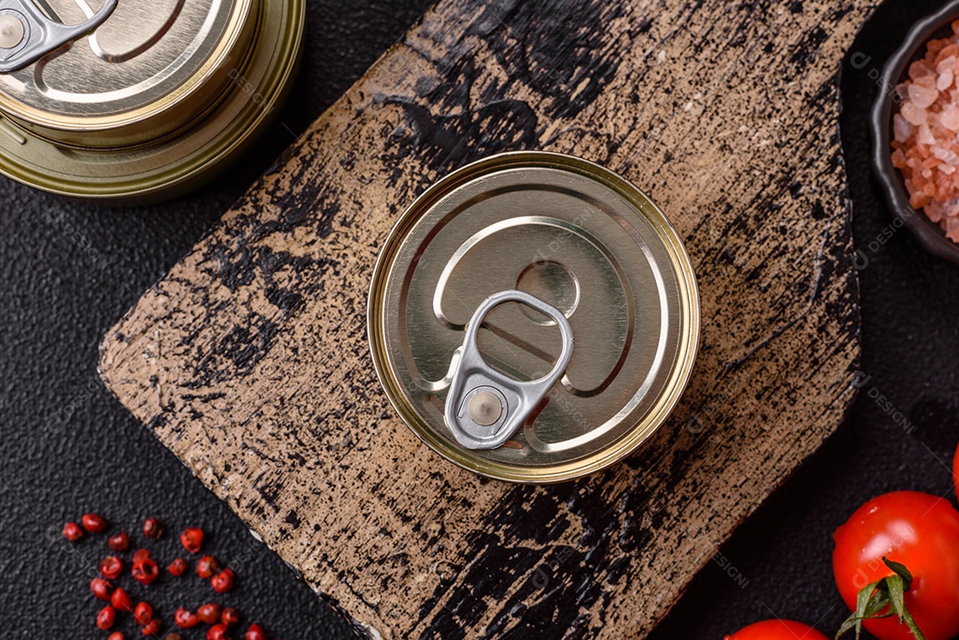 Lata metálica com carne ou peixe enlatado com chave para abri-lo sobre um fundo escuro de concreto