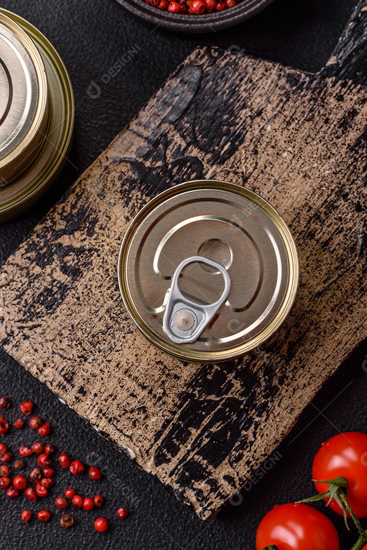 Lata metálica com carne ou peixe enlatado com chave para abri-lo sobre um fundo escuro de concreto