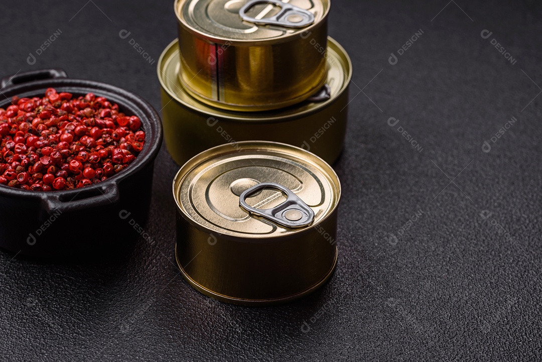 Lata metálica com carne ou peixe enlatado com chave para abri-lo sobre um fundo escuro de concreto