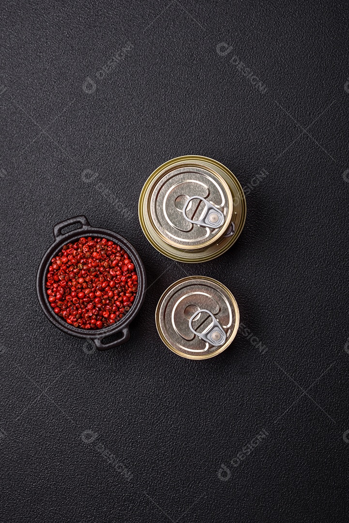 Lata metálica com carne ou peixe enlatado com chave para abri-lo sobre um fundo escuro de concreto