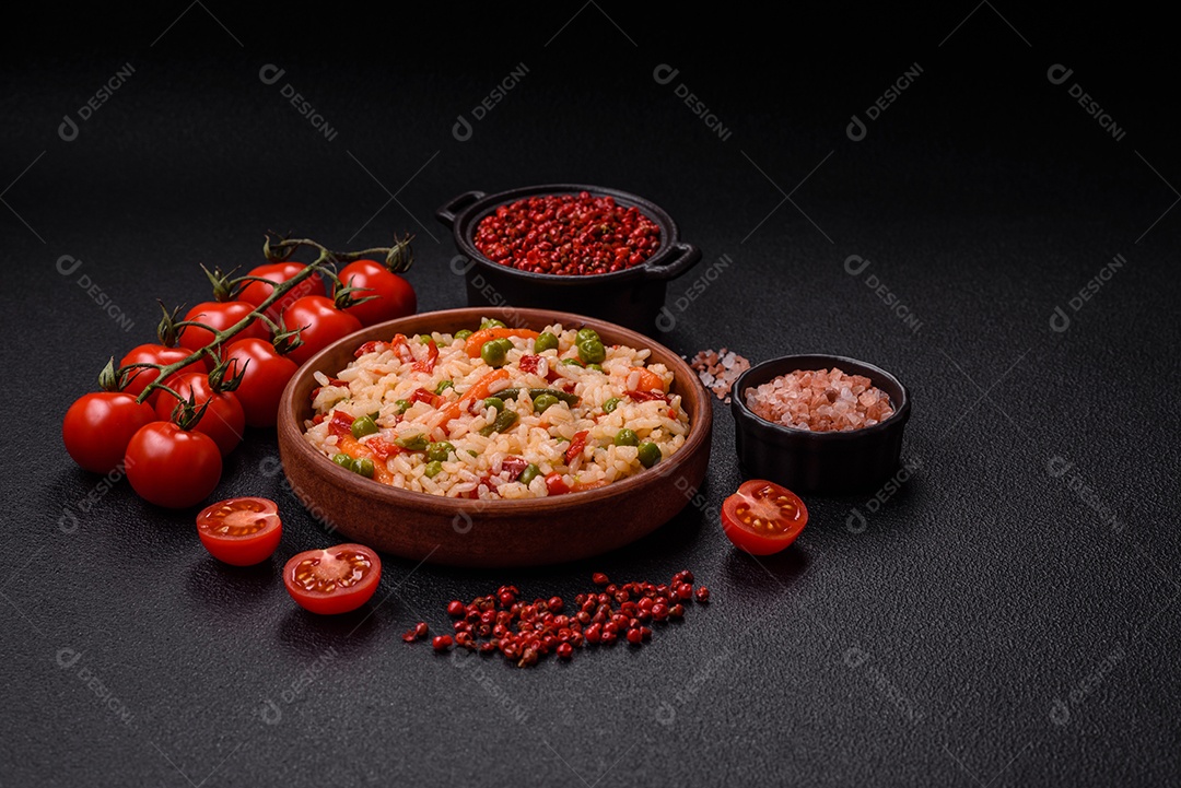 Delicioso arroz cozido com legumes cenouras, ervilhas e pimentões com sal e especiarias sobre um fundo escuro de concreto