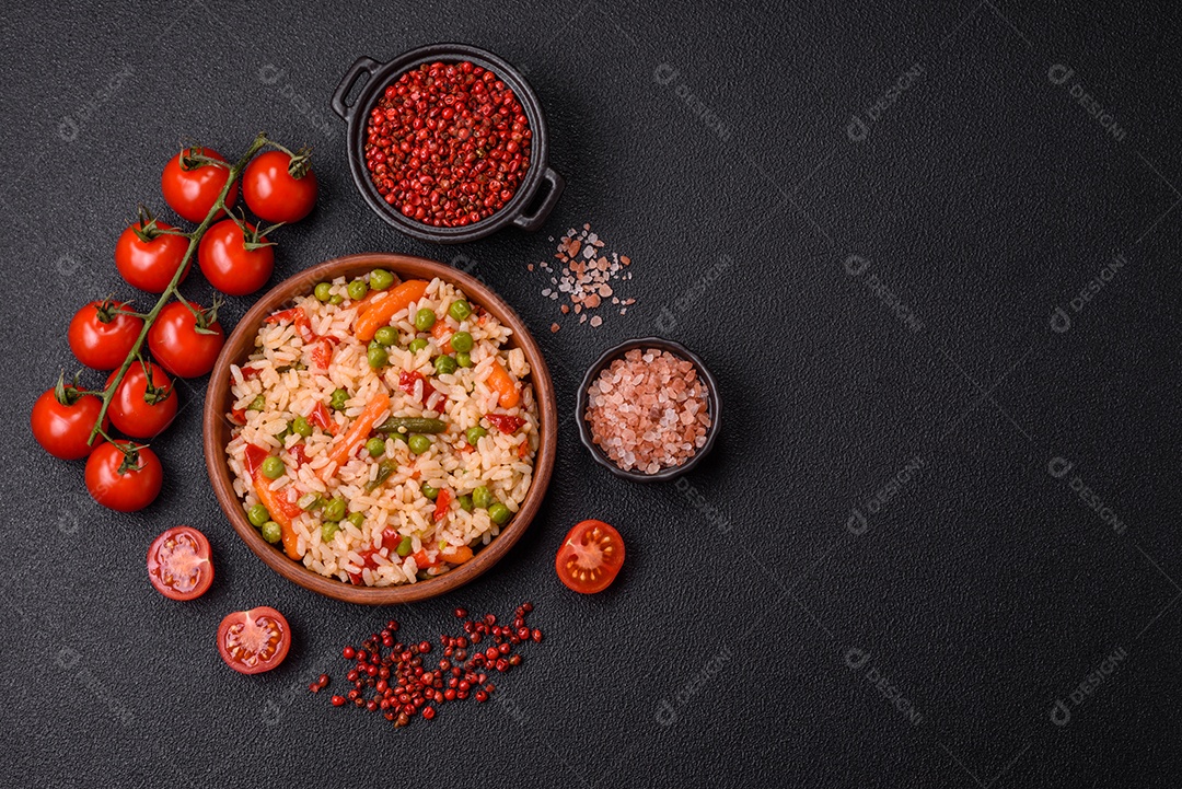 Delicioso arroz cozido com legumes cenouras, ervilhas e pimentões com sal e especiarias sobre um fundo escuro de concreto