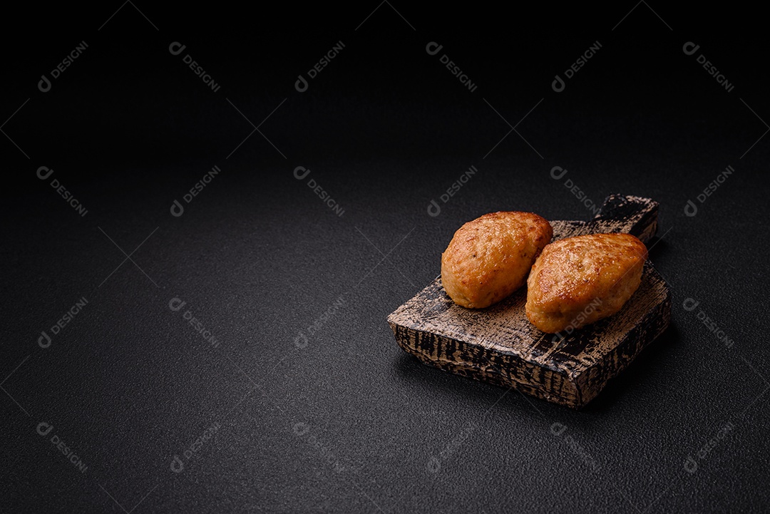 Deliciosas costeletas de peixe picado frito fresco com especiarias e ervas sobre um fundo escuro de concreto
