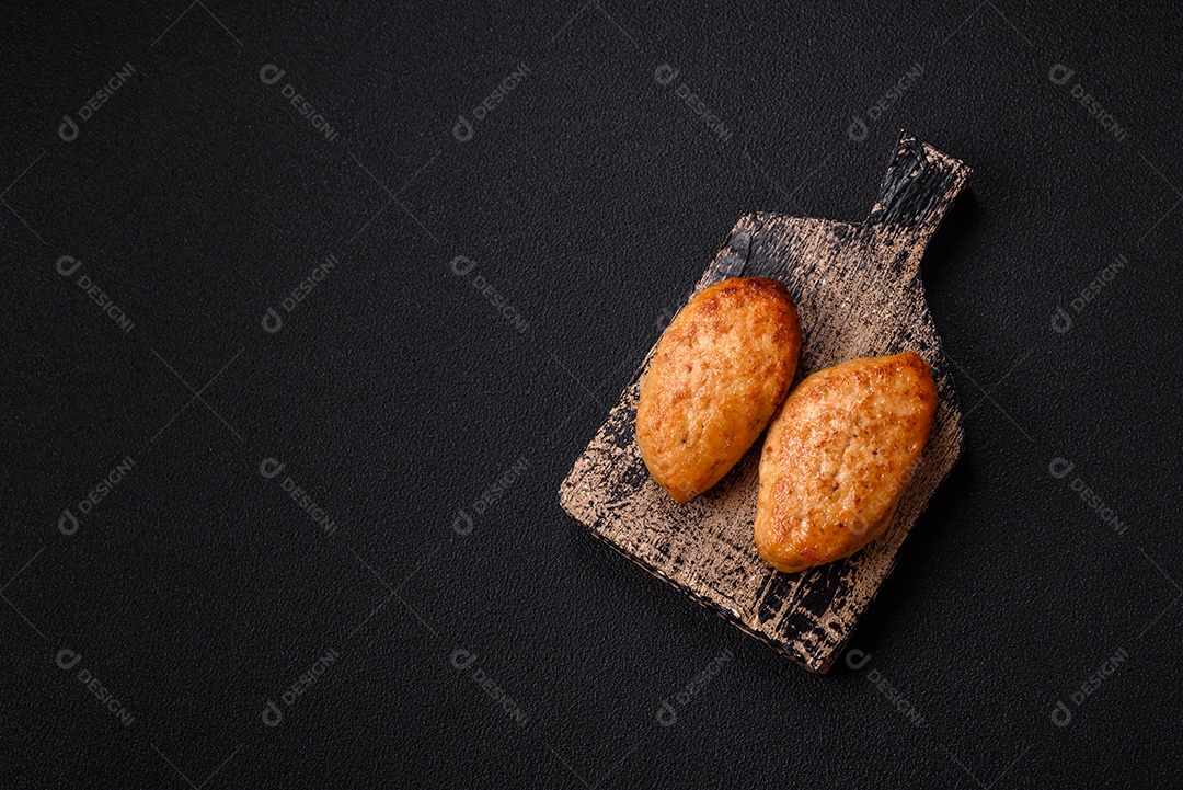 Deliciosas costeletas de peixe picado frito fresco com especiarias e ervas sobre um fundo escuro de concreto