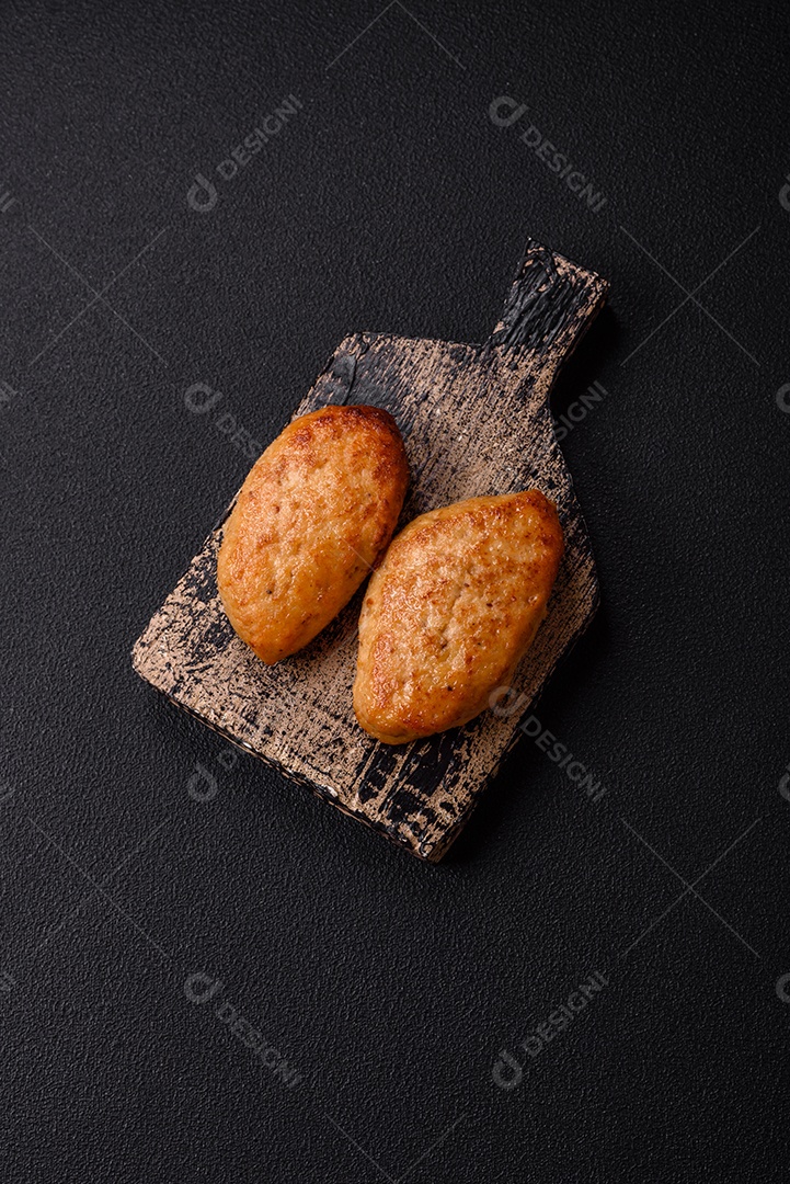 Deliciosas costeletas de peixe picado frito fresco com especiarias e ervas sobre um fundo escuro de concreto