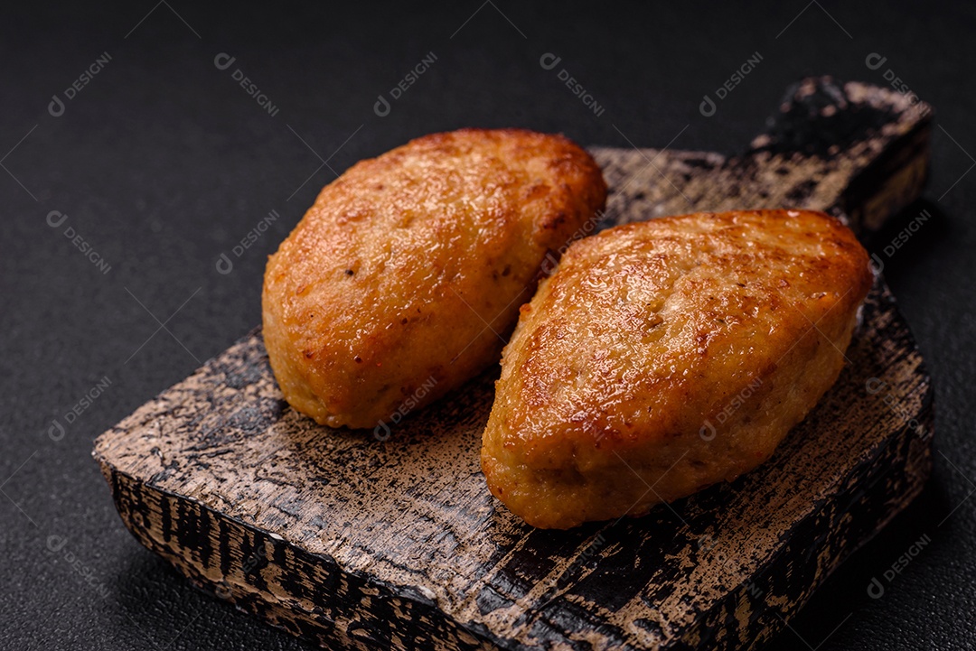 Deliciosas costeletas de peixe picado frito fresco com especiarias e ervas sobre um fundo escuro de concreto