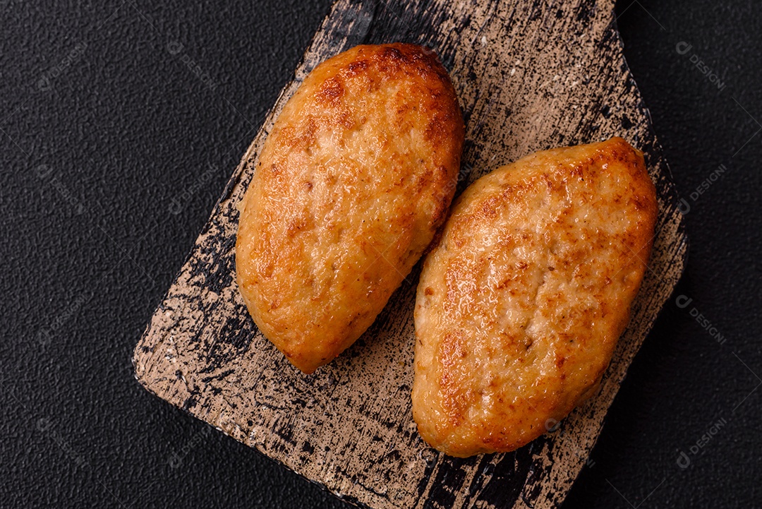 Deliciosas costeletas de peixe picado frito fresco com especiarias e ervas sobre um fundo escuro de concreto