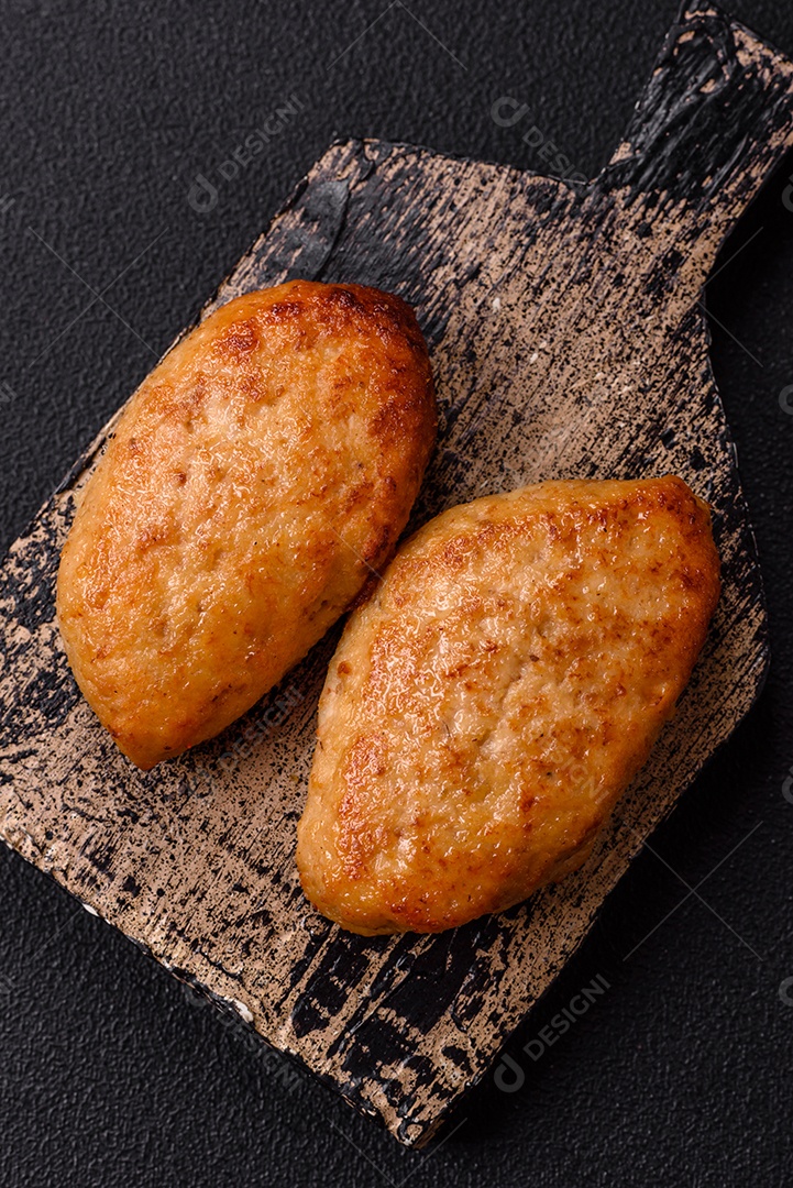 Deliciosas costeletas de peixe picado frito fresco com especiarias e ervas sobre um fundo escuro de concreto