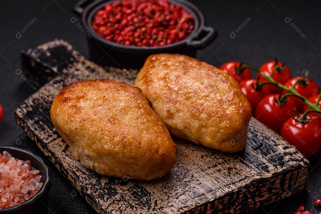 Deliciosas costeletas de peixe picado frito fresco com especiarias e ervas sobre um fundo escuro de concreto