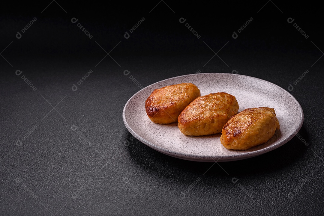 Deliciosas costeletas de peixe picado frito fresco com especiarias e ervas sobre um fundo escuro de concreto