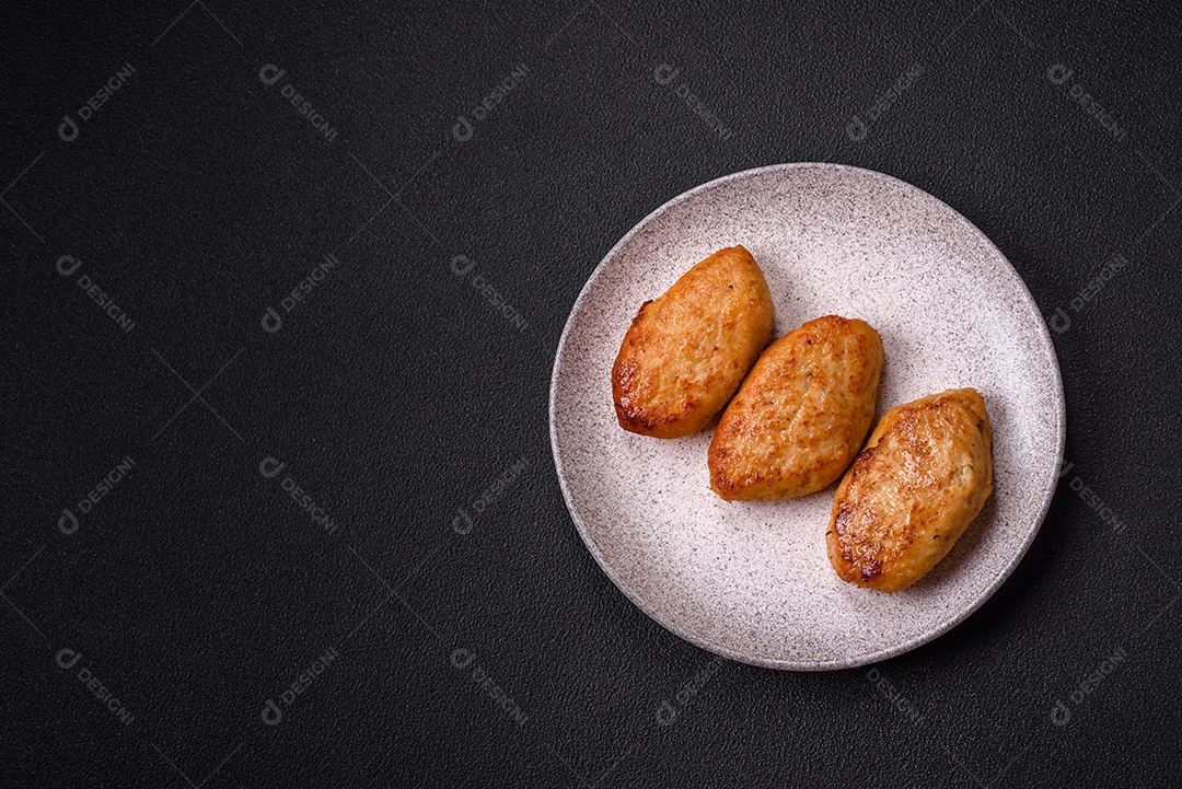 Deliciosas costeletas de peixe picado frito fresco com especiarias e ervas sobre um fundo escuro de concreto