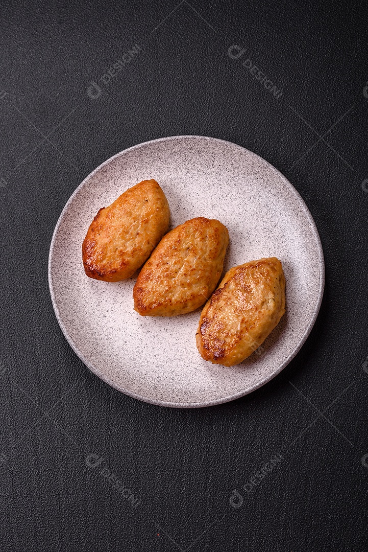 Deliciosas costeletas de peixe picado frito fresco com especiarias e ervas sobre um fundo escuro de concreto