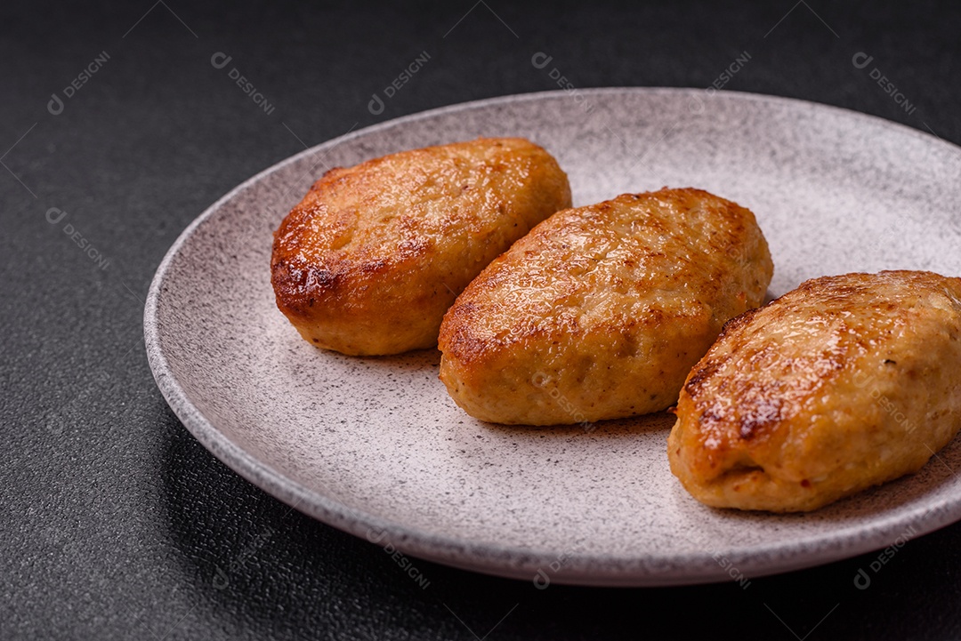 Deliciosas costeletas de peixe picado frito fresco com especiarias e ervas sobre um fundo escuro de concreto