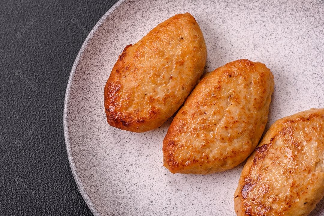 Deliciosas costeletas de peixe picado frito fresco com especiarias e ervas sobre um fundo escuro de concreto